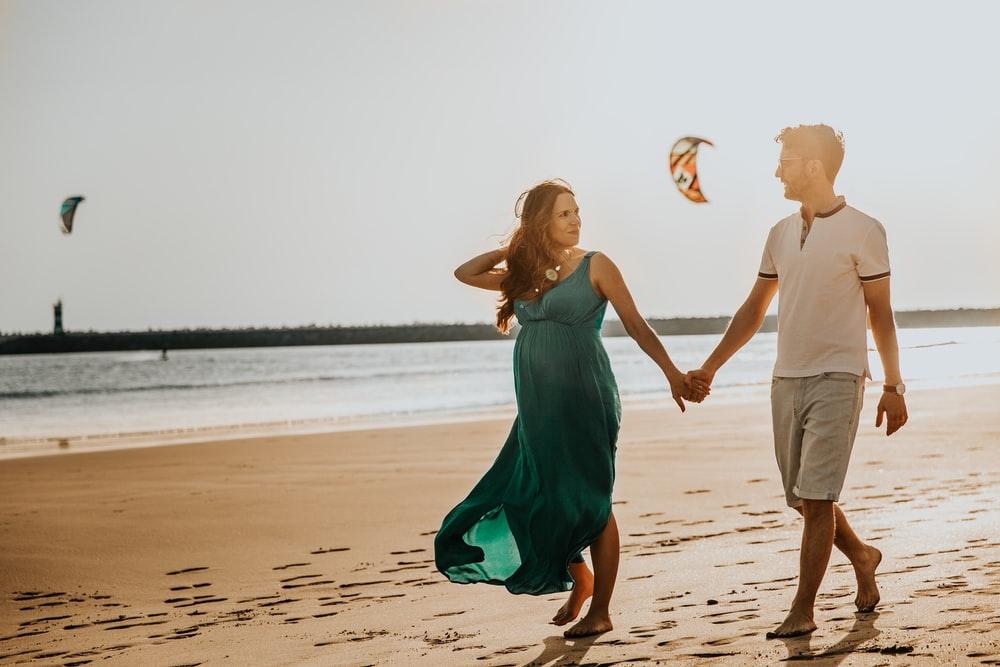 pregnant woman and man walking on beach